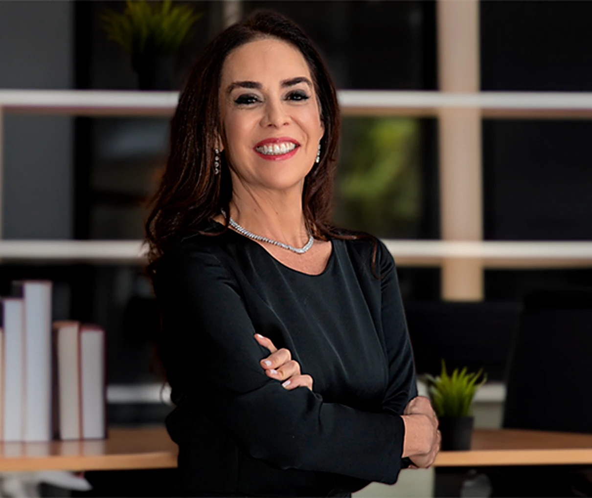 Renata Abalém em seu escritório, de braços cruzados e sorrindo